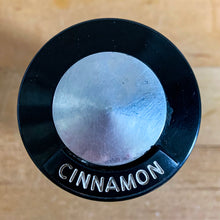Load image into Gallery viewer, Vintage aluminum cinnamon spice shaker with black lid featuring the name of the spice in white. Crafted by Kromex, USA, circa 1950s. A fabulous example of mid-century design and style! In vintage condition with age appropriate wear. Measures 2 1/4 x 4 inches