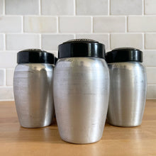 Load image into Gallery viewer, Vintage aluminum spice shaker with black lid featuring the name of the spice in white. Crafted by Kromex, USA, circa 1950s. A fabulous example of mid-century design and style! In vintage condition with age appropriate wear. Measures 2 1/4 x 4 inches