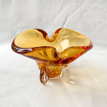 Load image into Gallery viewer, Vintage hand blown amber art glass ashtray. Crafted in Murano, Italy, 1960s. Perfect to use as intended or repurpose as a catchall or candy bowl and a lovely way to add mid mod style to your home's decor.
In good used vintage condition. A few minor flea bites at the base which are barely noticeable. The bottom is polished smooth.
Measures 6 3/4 x 4 x 4 inches