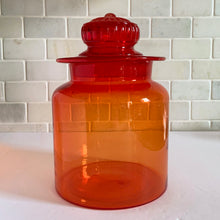 Load image into Gallery viewer, Striking vintage hand blown amberina apothecary canister jar with ground lid topped with an embossed flower detail. Takahashi Glass, Japan, circa 1970. This fabulous colour will liven up any room and it glows under black light!
In good vintage condition. There is chipping to the inside rim of the lid see photos. There are bubbles in the glass typical of the manufacturing process.
Measures 6 3/4 x 10 inches