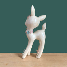 Load image into Gallery viewer, Adorable vintage mid-century era anthropomorphic deer ceramic figurine, glazed in iridescent white with blue rhinestone eyes, pink and blue flowers and gold gilt spaghetti details. Crafted by Lefton, Japan, circa 1950s. This sweet-faced deer is sure to delight everyone and it will make a wonderful addition to your Christmas holiday decor!
In good vintage condition. There is a chip to one blue flower, but otherwise excellent. Marked Japan and number 5845.
Measures 3 1/2 x 2 1/2 x 7 inches