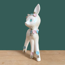 Load image into Gallery viewer, Adorable vintage mid-century era anthropomorphic deer ceramic figurine, glazed in iridescent white with blue rhinestone eyes, pink and blue flowers and gold gilt spaghetti details. Crafted by Lefton, Japan, circa 1950s. This sweet-faced deer is sure to delight everyone and it will make a wonderful addition to your Christmas holiday decor!
In good vintage condition. There is a chip to one blue flower, but otherwise excellent. Marked Japan and number 5845.
Measures 3 1/2 x 2 1/2 x 7 inches