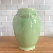 Load image into Gallery viewer, Side angle of the pale green urn vase showing the embossed handle motifs and tapered body