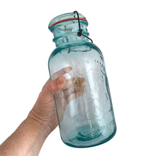 Load image into Gallery viewer, Vintage Perfect Seal aqua glass mason jar,featuring glass lid and wire bail closure. Produced by the Hamilton Glass Works in the early 20th century. These jars are fabulous for storing dry goods or may be repurposed as a vase. Perfect for farmhouse and cottage core decor. In as found condition. Measures 4 1/2 x 9 1/2 inches Capacity 2 quarts (1/2 gallon)