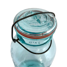 Load image into Gallery viewer, Vintage Perfect Seal aqua glass mason jar,featuring glass lid and wire bail closure. Produced by the Hamilton Glass Works in the early 20th century. These jars are fabulous for storing dry goods or may be repurposed as a vase. Perfect for farmhouse and cottage core decor. In as found condition. Measures 4 1/2 x 9 1/2 inches Capacity 2 quarts (1/2 gallon)