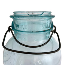 Load image into Gallery viewer, Vintage Perfect Seal aqua glass mason jar,featuring glass lid and wire bail closure. Produced by the Hamilton Glass Works in the early 20th century. These jars are fabulous for storing dry goods or may be repurposed as a vase. Perfect for farmhouse and cottage core decor. In as found condition. Measures 4 1/2 x 9 1/2 inches Capacity 2 quarts (1/2 gallon)