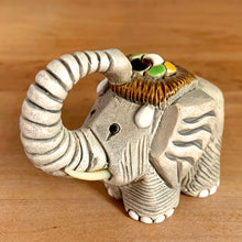 Load image into Gallery viewer, Artesania Rinconada elephant figurine number 9 vintage handmade art pottery Uruguay three-quarter left view trunk curled upward ivory tusks grey textured earthenware brown ribbed saddle green yellow flower accent