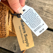 Load image into Gallery viewer, Lovely lightweight natural eastern Bali Ata Grass cross-body purse with loop closure, leather strap and cotton lining. Handcrafted by artisans using time-honoured techniques for Maker's Supply in Indonesia. Perfect for spring and summer, it adds a touch of casual sophistication to any feminine wardrobe.
The lining may have a water stain, but otherwise the purse is like-new and includes the original tags.
Measures 8 3/4 x 3 1/4 x 6 inches (28 inches with strap)