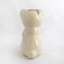 Load image into Gallery viewer, Adorable vintage miniature hand painted bear figurine featuring rosy cheeks, pink floral decals and gold gilt accents on a cream ground. Crafted by Shawnee Pottery, circa 1950s. This wee figurine is one of those rare, hard-to-find pieces that will make a delightful addition to your home's decor....perfect for a child's nursery!