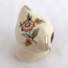 Load image into Gallery viewer, Adorable vintage miniature hand painted bear figurine featuring rosy cheeks, pink floral decals and gold gilt accents on a cream ground. Crafted by Shawnee Pottery, circa 1950s. This wee figurine is one of those rare, hard-to-find pieces that will make a delightful addition to your home's decor....perfect for a child's nursery!