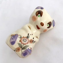 Load image into Gallery viewer, Adorable vintage miniature hand painted bear figurine featuring rosy cheeks, pink floral decals and gold gilt accents on a cream ground. Crafted by Shawnee Pottery, circa 1950s. This wee figurine is one of those rare, hard-to-find pieces that will make a delightful addition to your home's decor....perfect for a child's nursery!