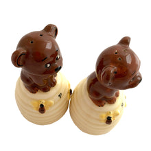 Load image into Gallery viewer, Vintage anthropomorphic bears on beehives ceramic salt and pepper shakers with plastic stoppers. Japan, 1970s. Add these adorable kitschy shakers to your collection!
In as found vintage condition, chip on bottom rim of one shaker, no cracks/repairs. Marked Japan.
Measures 2 1/4 x 2 1/4 x 4 1/2 inches