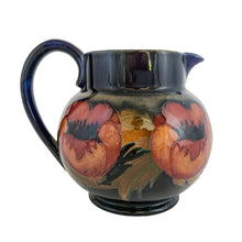 Load image into Gallery viewer, Vintage art nouveau "Big Poppy" pitcher featuring tubelined poppy flowers hand painted in muted shades of red on a cobalt blue ground. Crafted by Moorcroft Pottery, England, 1930s. A stunning piece of art pottery! In as found vintage condition with a chip to one side of the spout, see photos. Still great for display or have it repaired by a professional restorationist. Blue William Moorcroft signature with impressed mark "Made in England". 5 3/8 x 4 1/2 inches (incl. handle)