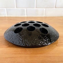 Load image into Gallery viewer, A rare vintage black amethyst glass flower frog with textured pattern and 16 holes. Crafted by the L. E. Smith Glass Company, USA, circa 1930s. When held up to a strong light, you'll be able to see the deep amethyst colour. Pair with your favourite vase or vessel to create a beautiful flower arrangement! In great condition, minor flea bites on several of the holes, see photos. Measures 4 1/2 x 1 inches