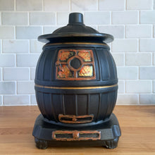 Load image into Gallery viewer, This vintage figural ceramic black pot belly stove cookie jar was crafted by McCoy Pottery in the 1960s. It's a must-have for any McCoy collector looking to add charm to their vintage cottage or farmhouse kitchen decor. This cookie jar is a perfect example of McCoy's expertise in creating high-quality and timeless pieces.
In excellent condition, no chip/cracks/repairs. There are a few tiny spots of glaze misses/loss.
Measures 6 3/4 x 7 x 10 3/8 inches