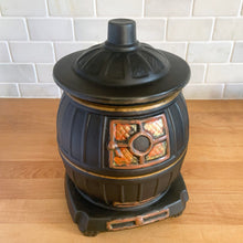 Load image into Gallery viewer, This vintage figural ceramic black pot belly stove cookie jar was crafted by McCoy Pottery in the 1960s. It's a must-have for any McCoy collector looking to add charm to their vintage cottage or farmhouse kitchen decor. This cookie jar is a perfect example of McCoy's expertise in creating high-quality and timeless pieces.
In excellent condition, no chip/cracks/repairs. There are a few tiny spots of glaze misses/loss.
Measures 6 3/4 x 7 x 10 3/8 inches