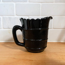 Load image into Gallery viewer, RARE! Gothic Victorian black pressed glass creamer jug. The lower 2/3 are stippled between smooth bands, while the top 1/3 is smooth. Produced by Davidson's, England, c1890 - 1910. A great piece to start a collection! In excellent vintage condition, free from chips/cracks/repairs. There is a manufacturer's defect on the underside of the foot near the mold line. Measures 2 3/4 x 3 1/2 inches (not including handle)