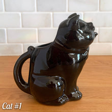 Load image into Gallery viewer, Vintage mid-century era redware ceramic cat creamer, featuring a figural seated cat, glazed is glossy black with a brown undertone and hand painted green eyes. Crafted by Shafford, Japan, 1950s. This kitschy creamer pours from the open mouth and works equally well as a decorative display piece. A solid example of postwar Japanese export ceramics with playful character and collectible appeal.
In excellent condition, no chips, cracks or repairs. Unmarked
Measures 5 1/4 x 3 x 5 1/2 inches