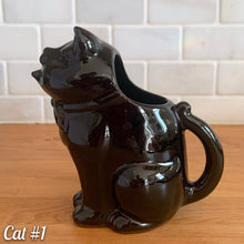 Load image into Gallery viewer, Vintage mid-century era redware ceramic cat creamer, featuring a figural seated cat, glazed is glossy black with a brown undertone and hand painted green eyes. Crafted by Shafford, Japan, 1950s. This kitschy creamer pours from the open mouth and works equally well as a decorative display piece. A solid example of postwar Japanese export ceramics with playful character and collectible appeal.
In excellent condition, no chips, cracks or repairs. Unmarked
Measures 5 1/4 x 3 x 5 1/2 inches