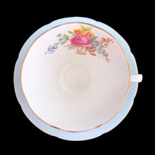 Load image into Gallery viewer, This lovely vintage art deco style bone china teacup and saucer features a pale blue exterior and gold gilt details with subtle scalloped rims. The cup's white interior and centre of the saucer, each display a hand painted bouquet of pink roses and colourful flowers. Crafted by Royal Grafton, England, 1950s. A lovely way to enjoy a cuppa tea!
In excellent condition, no chips, cracks or repairs. Maker's mark on the bottom.
Teacup measures 3 1/2 x 3 inches. Saucer measures 5 3/8 inches