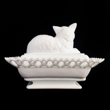 Load image into Gallery viewer, Gorgeous vintage white cat-on-nest milk glass dish featuring a lovely lace edge and blue glass eyes. Crafted by Westmoreland Glass, USA, circa 1950s/60s. A unique piece of pressed glass to use as a candy dish or catchall. A wonderful gift for the vintage glass enthusiast or cat lover!
In excellent condition, no chips, cracks or repairs. Lid and base have Westmoreland's maker's mark.
Measures 8 1/8 x 5 1/8 x 6 inches