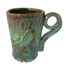 Load image into Gallery viewer, Vintage watery blue, green, ochre high fired drip glaze studio pottery mug featuring applied and debossed dragonflies with sculpted handle and scalloped base. Signed AA. This gorgeous one-of-a-kind handmade vessel is perfect for any hot beverage.
In excellent condition, no chips, cracks or repairs. Typical manufacturing glaze bubbles.
Measures 3 7/8 x 5 1/2 inches (5 7/8" incl. handle)
Capacity 16oz