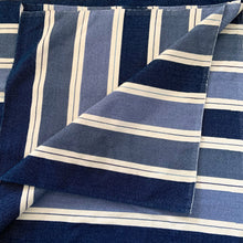 Load image into Gallery viewer, This queen-size blanket represents five decades of weaving mastery from Tissage MaGély Weaving in New Brunswick. Hand-loomed in wool and cotton by the Levesque family, its multi-blue and white striped pattern reflects the studio's commitment to traditional textile arts since 1973. Substantial enough for layering or as a primary bedcover, it delivers both visual character and genuine warmth—a functional heirloom piece for collectors of artisan-made home textiles.
