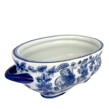 Load image into Gallery viewer, Three-quarter front view of Bombay Company blue and white chinoiserie oval jardiniere, showing the butterfly motif on the left panel, chrysanthemum and floral sprays, and solid cobalt handles
