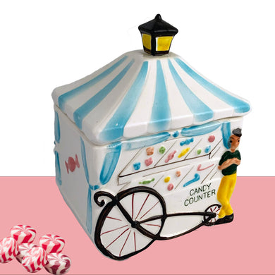 Sweet and rare! Vintage Candy Counter lidded ceramic canister, features a candy vendor alongside his candy cart. The cart has a blue and white striped awning, topped with a lantern and the cart displays a selection of colourful candies. Crafted by Napco Originals, circa 1950s. Marked E-575 Japan on the bottom. A great piece of mid-century kitsch to add to your home or kitchen decor  In excellent condition, free form chips/cracks.  Measure approximately 4 3/4 x 3 1/4 x 6 inches