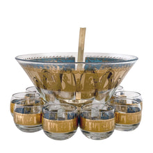 Load image into Gallery viewer, Fabulous vintage mid-century modern Carousel punch bowl with ten matching roly poly glasses and gold toned metal ladle. The glassware is decorated with carousel horses and carriages in 22kt gold on teal blue paint. Crafted by Colony, USA, circa 1960s. Perfect for serving eggnog, alcohol or non-alcohol punch at your next soirée! Stunning doesn't quite describe this fabulous set which is sure to be a standout at your next party!