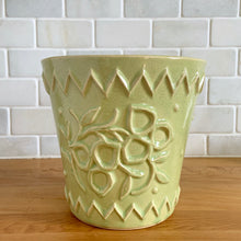 Load image into Gallery viewer, Rare vintage chartreuse green planter pot with embossed flower motif and zig zag borders. Crafted by McCoy Pottery, 1954. This rare planter is must for any McCoy art pottery collector. A wonderful piece to elevate your home and garden decor or to give as a gift!
In as found vintage condition, chip to the rim and crack, no repairs. Normal age-related crazing and manufacturer's glaze pops. Maker's mark on the bottom.
Measures 6 1/2 x 6 1/8 inches