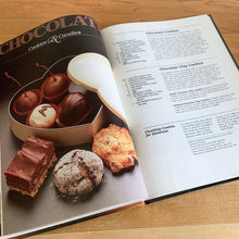 Load image into Gallery viewer, Better Homes and Gardens is known for its fabulous cookbooks. This hardcover cookbook focuses on Chocolate recipes. Its 96 pages are filled with amazing recipes along with many colour photographs. Originally published by Meredith Corporation, USA, 1984. This is the fifth printing, 1985. In great vintage condition with normal age-related yellowing.