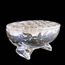 Load image into Gallery viewer, This exquisite vintage flowerlite features a clear oval or oblong shape adorned with a delicate silver overlay of orchid flowers. Crafted by Viking Art Glass in the 1950s, it includes a glass flower frog designed to hold two taper candles and rests on elegant Chinoiserie-style scrolled feet. Ideal for creating sophisticated floral arrangements, this Hollywood Regency piece enhances any space with timeless charm, whether illuminated by candlelight or displayed on its own in both modern and vintage interiors.