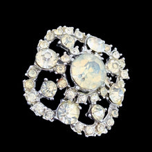 Load image into Gallery viewer, Angled front view of vintage rhinestone swirl brooch with large central stone and mixed-size clear stones, silver-tone