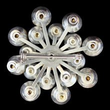 Load image into Gallery viewer, Reverse of vintage rhinestone starburst brooch showing silver-tone radial spokes, foil-backed stone settings, and rollover pin clasp