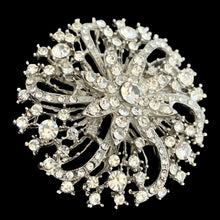 Load image into Gallery viewer, Angled front view of vintage silver-tone starburst brooch with clear rhinestones in swirling radial pattern