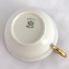 Load image into Gallery viewer, Antique bone china teacup and saucer is absolutely stunning! Both have a subtle scalloped shape. The white cup is decorated in a design of pale blue floral bouquets and bows on a cobalt blue band with gold gilt details. Produced by Aynsley, England. Excellent condition, free from chips, cracks and repairs. The pattern number 3410 is painted on the saucer. The stamped maker's mark indicates production between 1905 - 1925. Teacup measures 3 1/2 x 2 1/4 inches | Saucer measures 5 5/8 inches