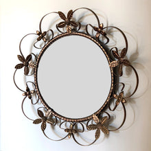 Load image into Gallery viewer, Bring on the mid-century vintage vibes with this round convex mirror encased in copper toned metal featuring a pierced metal band, surrounded with scrolled metal sections and impressed metal flowers. The mirror has a wood backing and a built in wall hanger. Circa 1950s. This beauty is ready to hang and is sure to add a special touch of glam to your bath, bedroom or entranceway! In excellent condition. Measures 17 1/2 inches in diameter