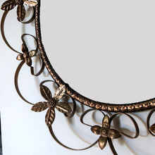 Load image into Gallery viewer, Bring on the mid-century vintage vibes with this round convex mirror encased in copper toned metal featuring a pierced metal band, surrounded with scrolled metal sections and impressed metal flowers. The mirror has a wood backing and a built in wall hanger. Circa 1950s. This beauty is ready to hang and is sure to add a special touch of glam to your bath, bedroom or entranceway! In excellent condition. Measures 17 1/2 inches in diameter