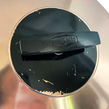 Load image into Gallery viewer, Vintage copper/rose gold toned aluminum dome cake carrier keeper featuring a black bakelite handle and an illustration in black of a sliced cake with the word "CAKE" below in a cute vintage font and locking levers to hold the dome securely to the base. The perfect vessel to store your home-baked or store bought confections! In as found vintage condition with wear to the black at the top of the dome, age-related wear. Fits up to a 10 1/2 x 5 inch cake Overall measures 14 1/2 x 8 inches