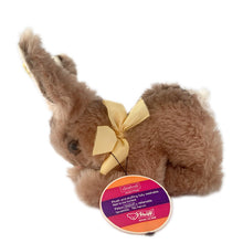 Load image into Gallery viewer, Vintage stuffed animal tan light brown bunny rabbit. Washable Dralon plush material. Hand embroidered pink nose and brown mouth, brown glass eyes with black pupils, and light beige felt rear foot pads. Gold satin ribbon and round red, blue and yellow tag bearing the name Cosy Mummy. Brass button-in-ear yellow and black tag 494020 and paper tag. Steiff, Germany 1970s. This bunny rabbit sits in a seated or reclining position. In excellent condition. Measures 8 1/2 inches or 22cm