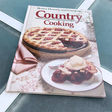 Load image into Gallery viewer, Better Homes and Gardens is known for its fabulous cookbooks. This hardcover cookbook focuses on country cooking recipes and designs. Its 96 pages are filled with amazing recipes along with many colour photographs. Originally published by Meredith Corporation, USA, 1983. This is the third printing 1984. In great vintage condition with normal age-related yellowing.