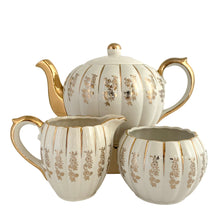 Load image into Gallery viewer, Vintage W777 teapot, creamer and sugar set features vertically ribbed cream body, with cream ground and gold gilt flowers and details. Crafted by Gibsons, England, circa 1950s. Whether the star of your high tea service or for everyday use, you'll appreciate this beautifully decorated quality earthenware.
In excellent condition, no chips/cracks/repairs.