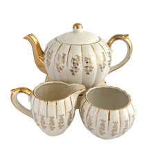 Load image into Gallery viewer, Vintage W777 teapot, creamer and sugar set features vertically ribbed cream body, with cream ground and gold gilt flowers and details. Crafted by Gibsons, England, circa 1950s. Whether the star of your high tea service or for everyday use, you'll appreciate this beautifully decorated quality earthenware.
In excellent condition, no chips/cracks/repairs.