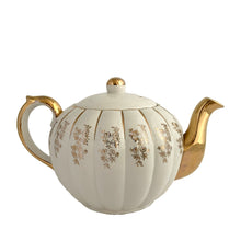 Load image into Gallery viewer, Vintage W777 teapot, creamer and sugar set features vertically ribbed cream body, with cream ground and gold gilt flowers and details. Crafted by Gibsons, England, circa 1950s. Whether the star of your high tea service or for everyday use, you'll appreciate this beautifully decorated quality earthenware.
In excellent condition, no chips/cracks/repairs.