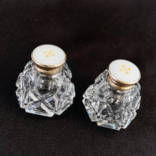 Load image into Gallery viewer, A pair of traditional vintage round paneled shaped cut crystal salt and pepper shakers in the art deco style featuring an "X" and diamond pattern with sterling silver mother-of-pearl lids.   In excellent condition, no chips or cracks. Marked 925 Sterling.  Measures 1 1/2 x 1 3/4 inches