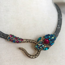 Load image into Gallery viewer, Make a bold statement with this iconic Betsey Johnson necklace from the coveted Dark Shadows collection. Featuring a dramatic pavé crystal snake head and tail, this choker-style necklace coils with edgy glamour and gothic elegance. Perfect for lovers of designer jewelry, statement chokers, and Betsey Johnson’s signature dark, whimsical aesthetic. Whether styled with evening wear or layered into a modern edgy outfit, this necklace is a true collectible showstopper.
In excellent condition. Signed BJ