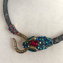 Load image into Gallery viewer, Make a bold statement with this iconic Betsey Johnson necklace from the coveted Dark Shadows collection. Featuring a dramatic pavé crystal snake head and tail, this choker-style necklace coils with edgy glamour and gothic elegance. Perfect for lovers of designer jewelry, statement chokers, and Betsey Johnson’s signature dark, whimsical aesthetic. Whether styled with evening wear or layered into a modern edgy outfit, this necklace is a true collectible showstopper.
In excellent condition. Signed BJ
