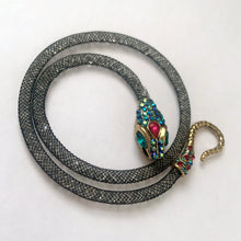 Load image into Gallery viewer, Make a bold statement with this iconic Betsey Johnson necklace from the coveted Dark Shadows collection. Featuring a dramatic pavé crystal snake head and tail, this choker-style necklace coils with edgy glamour and gothic elegance. Perfect for lovers of designer jewelry, statement chokers, and Betsey Johnson’s signature dark, whimsical aesthetic. Whether styled with evening wear or layered into a modern edgy outfit, this necklace is a true collectible showstopper.
In excellent condition. Signed BJ