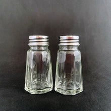 Load image into Gallery viewer, Sail away to flavor-town with this retro vintage set of salt and pepper shakers! These 50s-style clear pressed glass shakers come feature eight panels and flat top stainless steel screw-on lids. Season your food with a real blast from the past! The glass is in excellent condition, free from chips/cracks. The lids have very minor wear, see photos. Marked "TAIWAN". Measures 1 3/8 x 3 inches